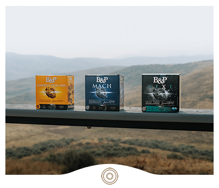 B&P shotshell boxes on a shelf with hills in the background