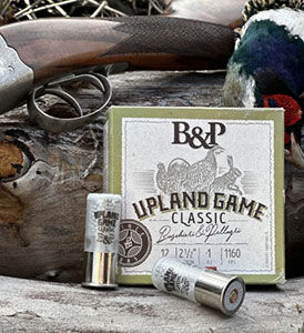 Upland Game Classic box and shotshells next to a shotgun and a dead pheasant